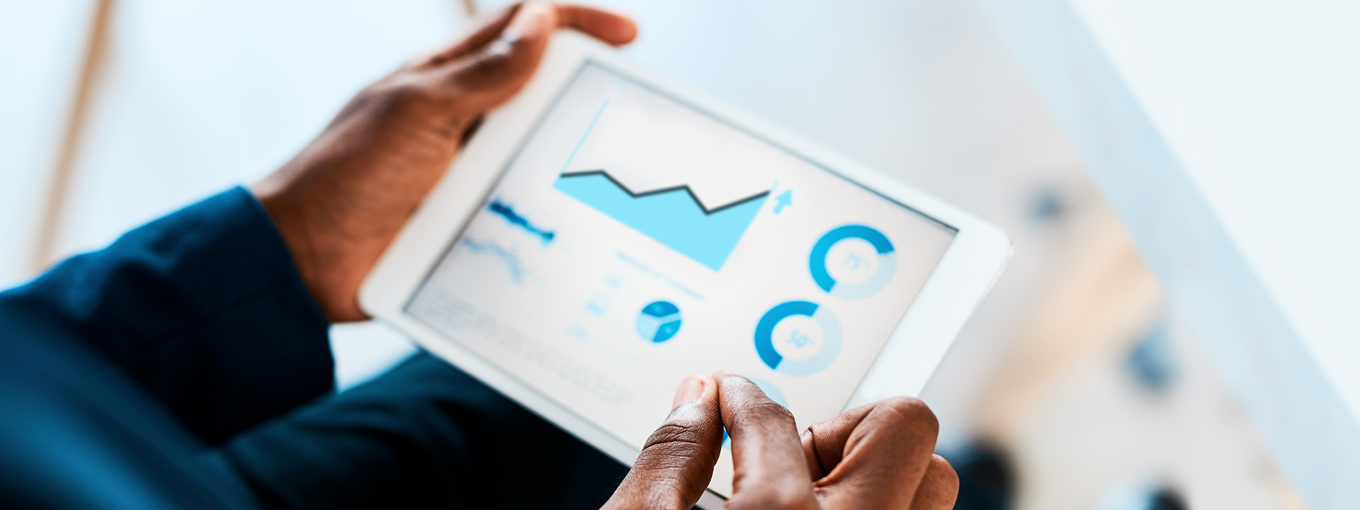 Hands holding tablet showing graphs