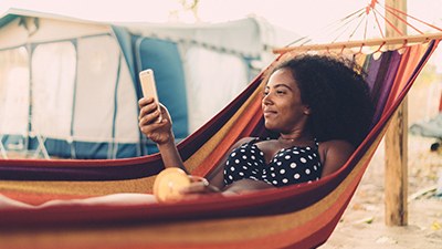 A woman lying in a hammock, holding her phone